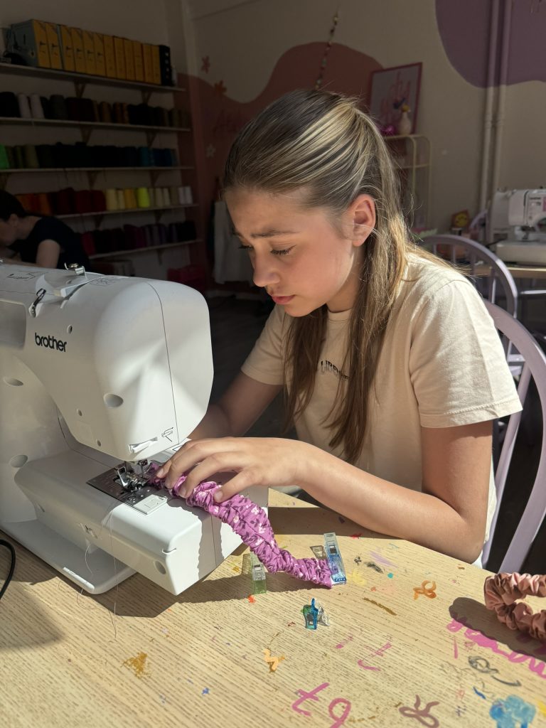 Een jongere aan het naaien tijdens de naailes voor tieners
